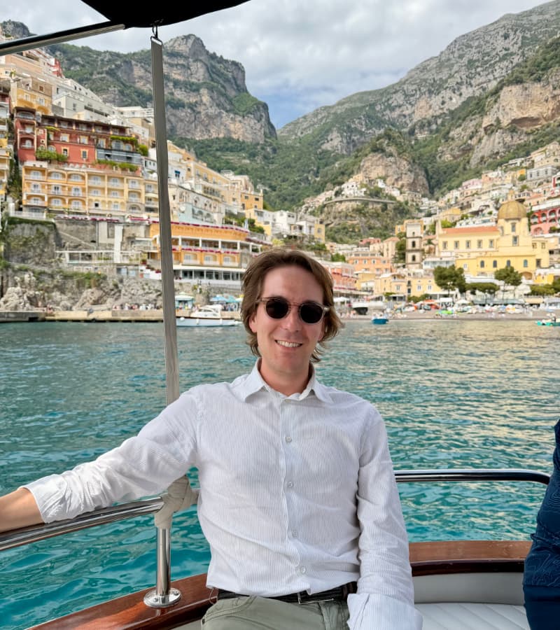 Gianmaria picture sitting on a boat with Positano in the background