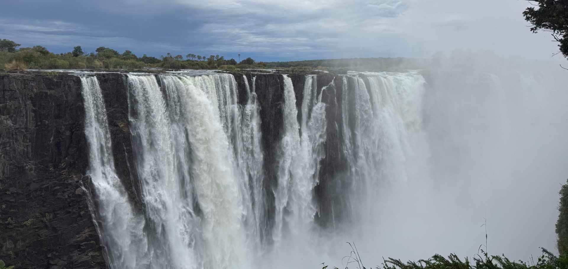 Massive sheets of water plunge over the edge of Victoria Falls into the deep basalt chasm