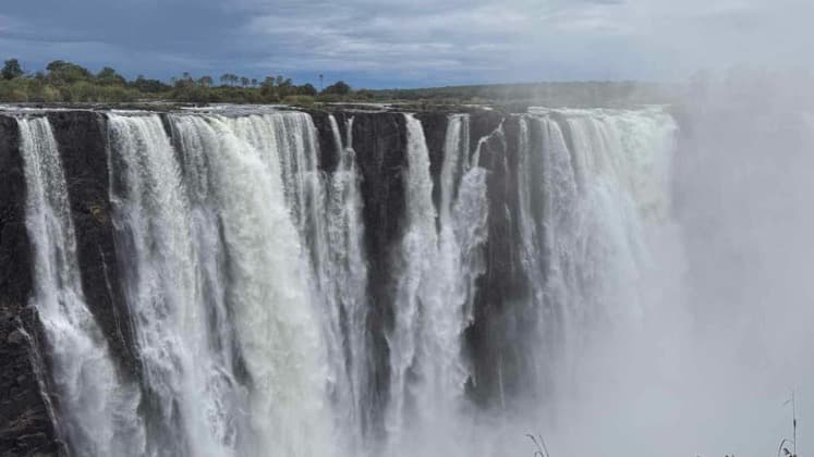 Massive sheets of water plunge over the edge of Victoria Falls into the deep basalt chasm