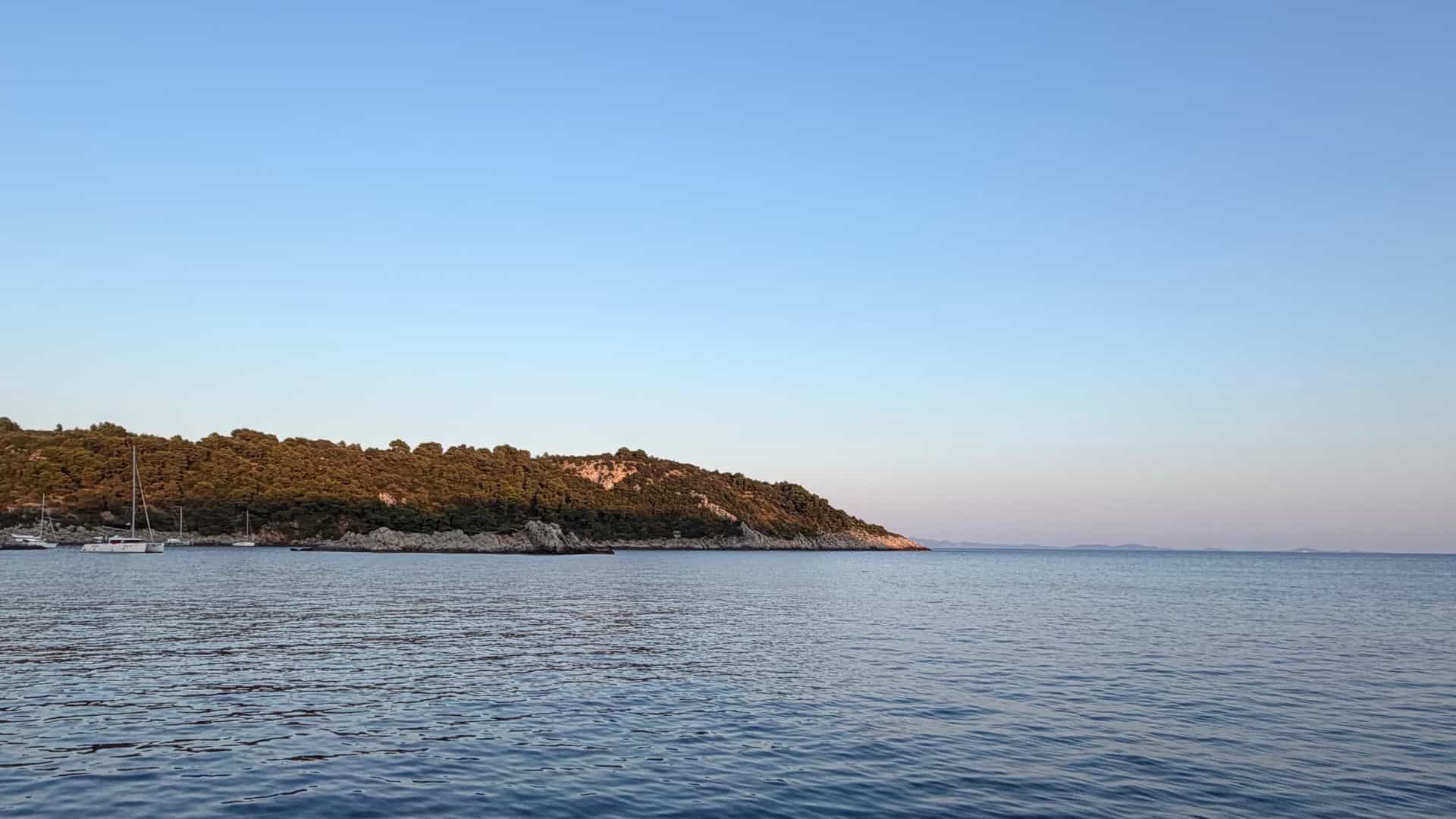 Clear blue waters of the Southern Dalmatian Channel framed by sailboat rigging near distant limestone hills.