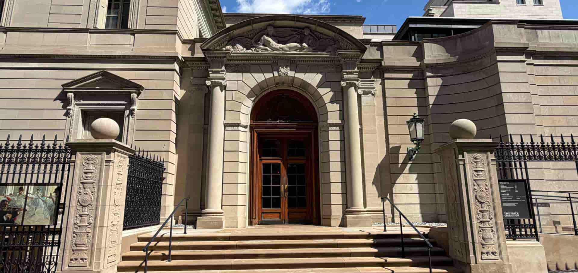 Grand limestone entrance facade and heavy wooden doors of The Frick Collection on Fifth Avenue.