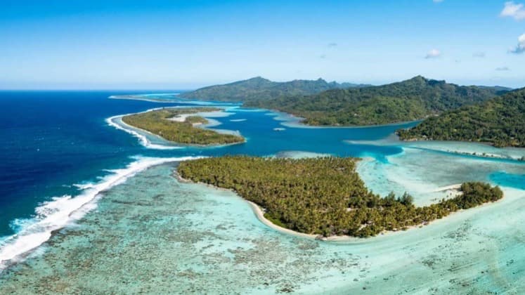 Aerial view of lush volcanic islands surrounded by turquoise lagoons and barrier reefs.