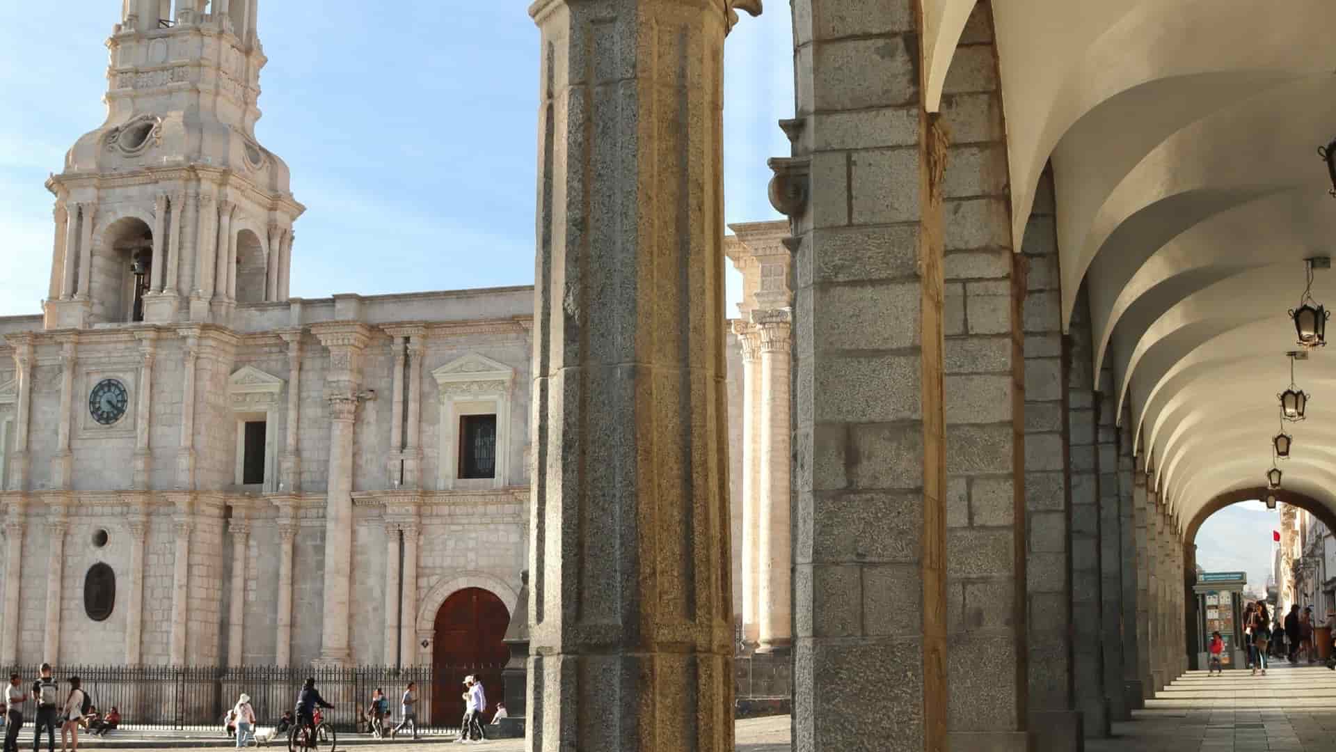 Classic carved stone columns and arches framing the historic Plaza de Armas in Arequipa.