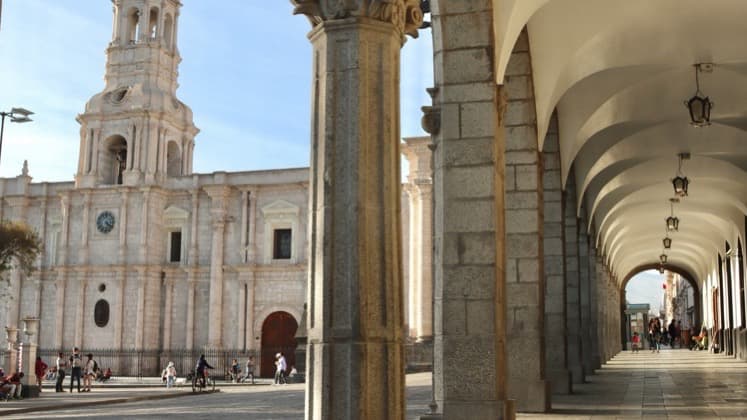 Classic carved stone columns and arches framing the historic Plaza de Armas in Arequipa.