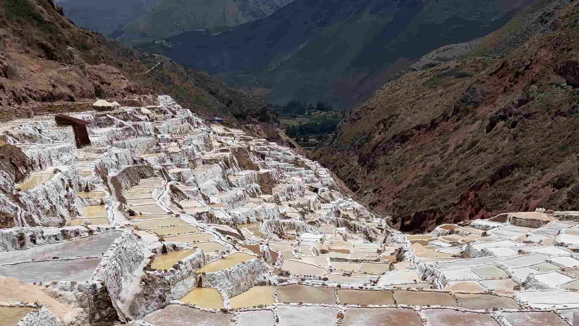 Cascading white salt evaporation ponds step down the red canyon slope in Peru.