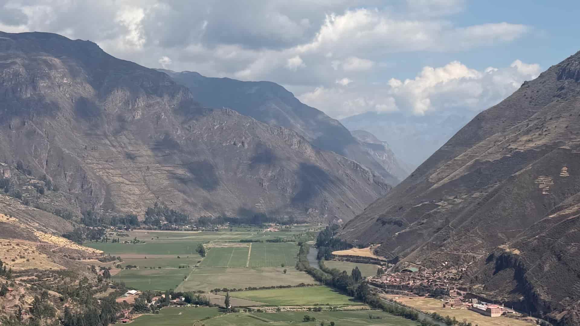 Panoramic view of the green Urubamba River valley flanked by steep mountain slopes.