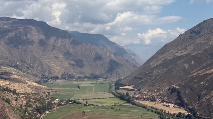 Panoramic view of the green Urubamba River valley flanked by steep mountain slopes.