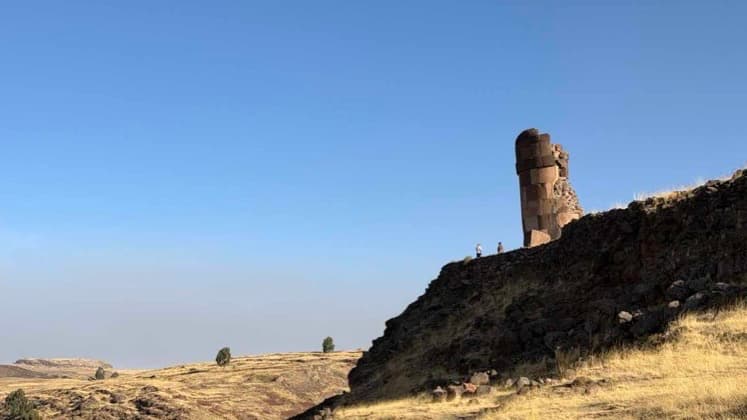 Panoramic view of grassy plains and a calm lake under a clear blue sky.