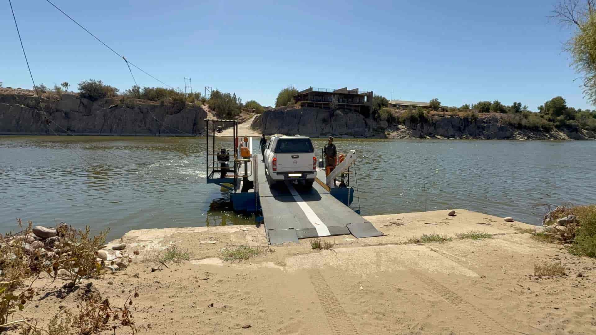 A white 4x4 vehicle secured on the cable-guided pontoon ferry crossing the Orange River