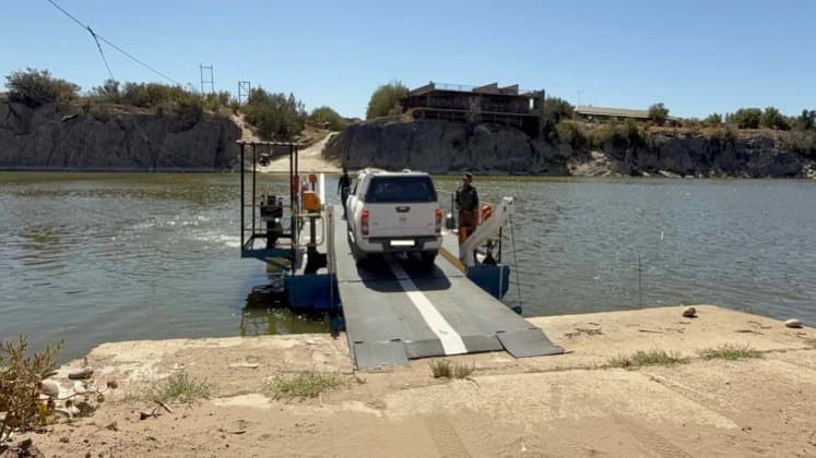A white 4x4 vehicle secured on the cable-guided pontoon ferry crossing the Orange River