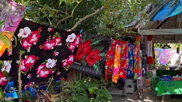 Vibrant floral pareos and clothing hanging on outdoor lines at a workshop in Bora Bora.