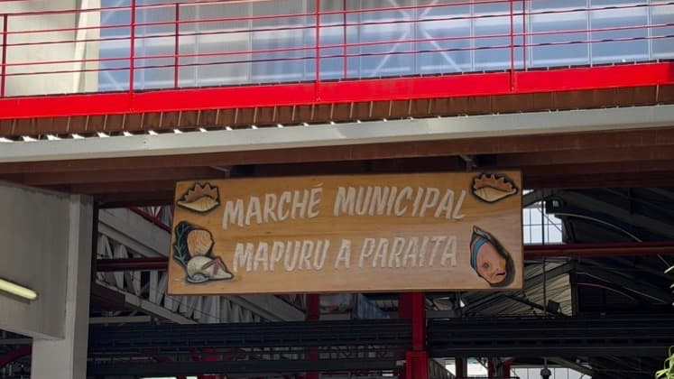 Wooden sign reading Marché Municipal Mapuru a Paraita adorned with decorative seashell carvings.