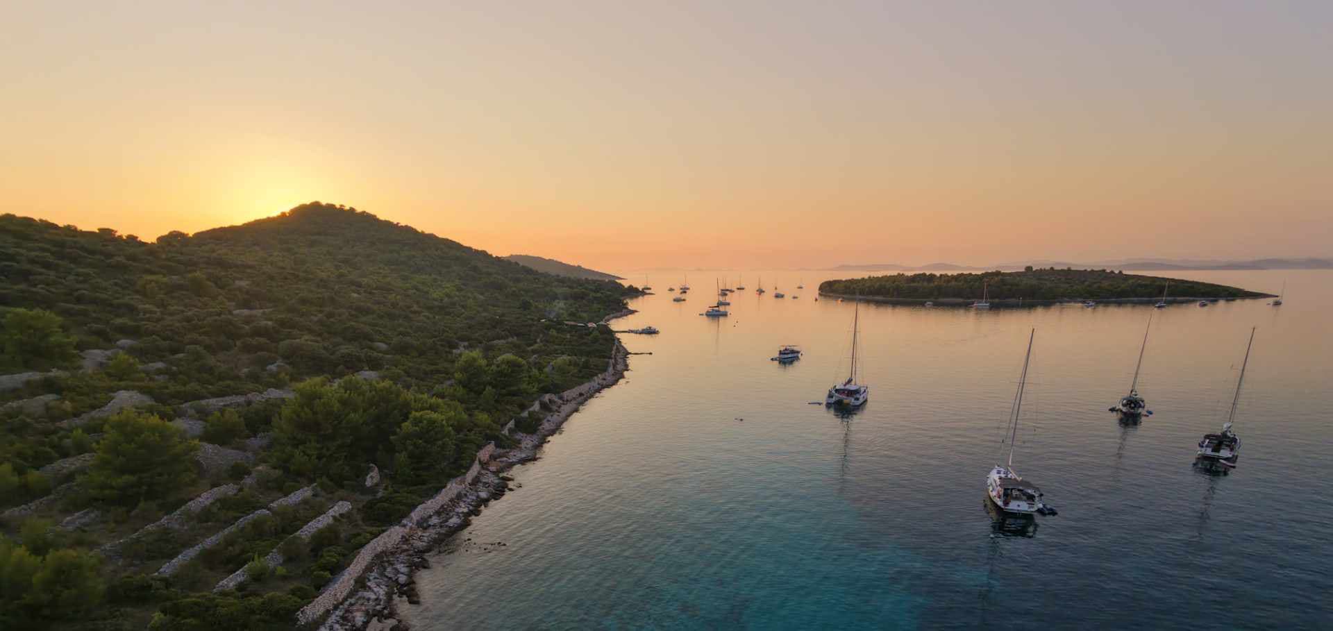 Sailboats anchored in a calm Croatian bay at sunset during an Adriatic voyage