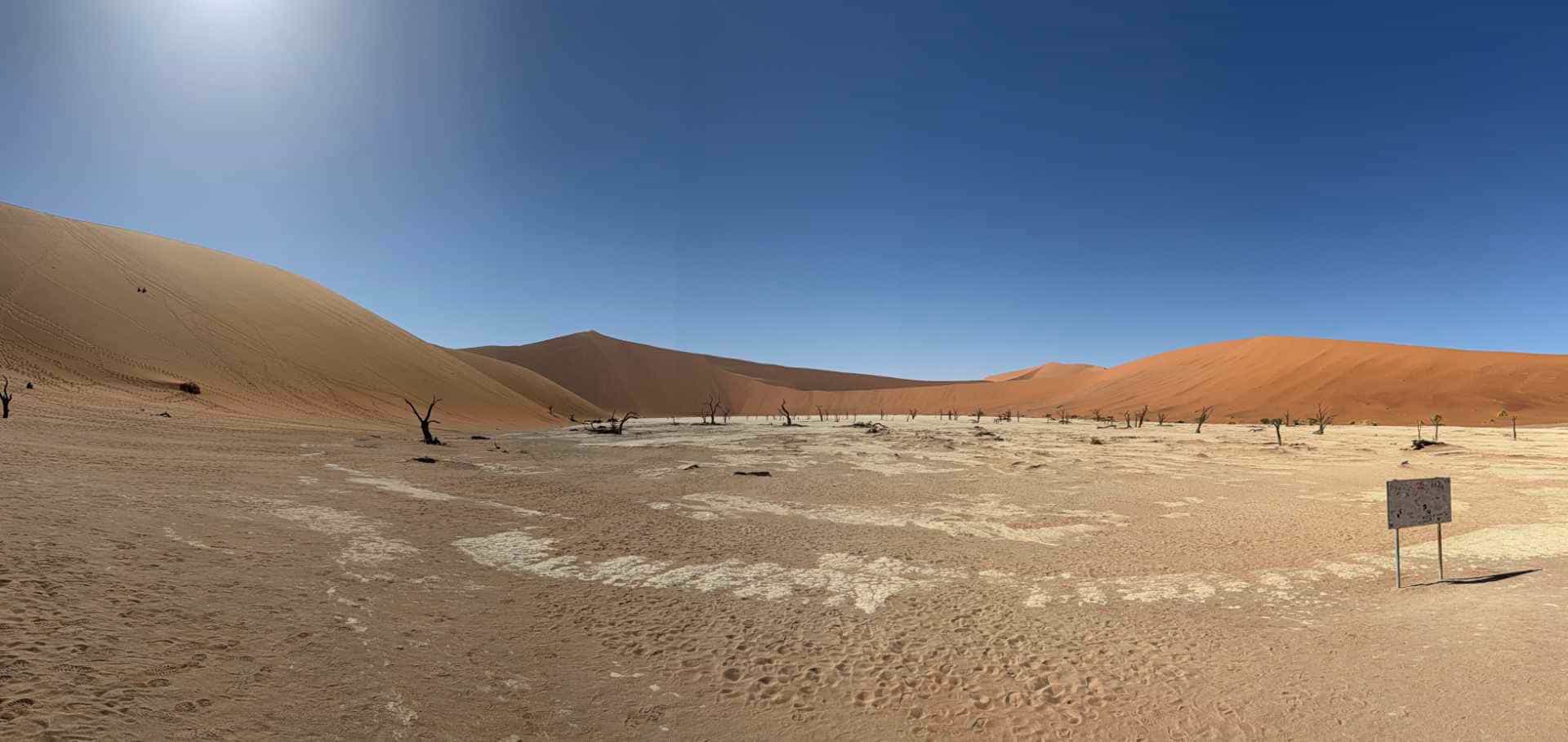 Panoramic view of the bone-white clay basin surrounded by massive orange sand dunes