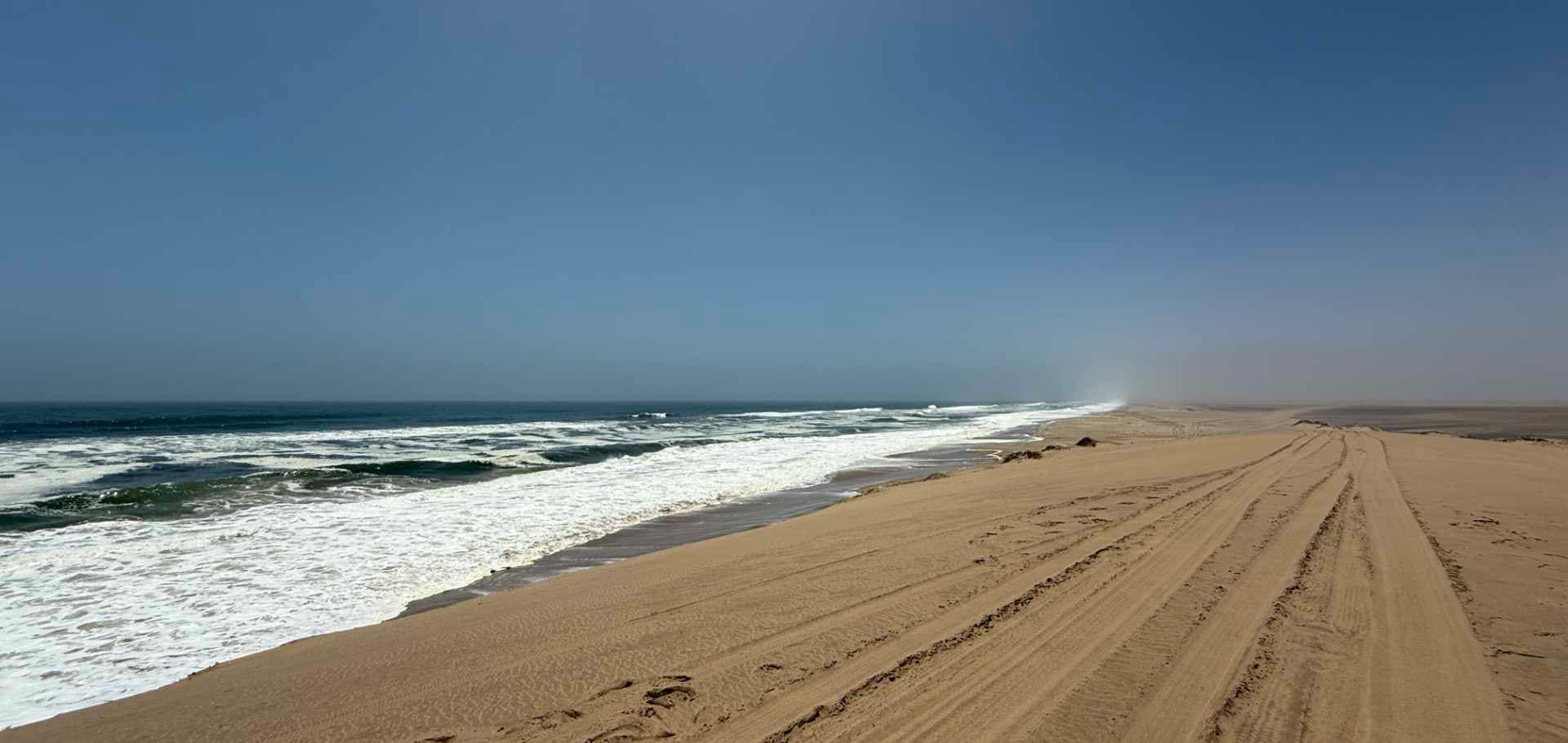 A convoy of 4x4 vehicles parked along a high desert ridge overlooking the Atlantic Ocean
