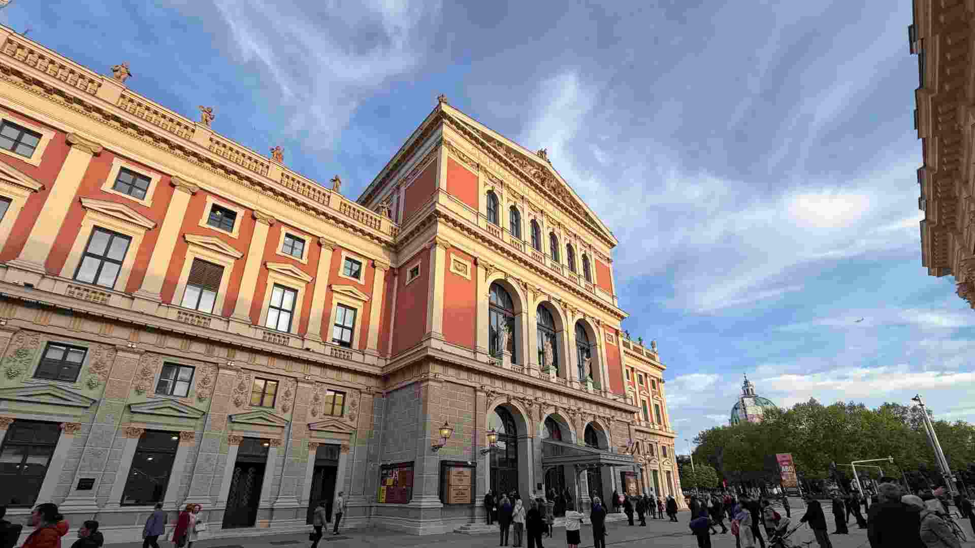 Neoclassical red facade of the historic Musikverein building under a blue sky in Vienna