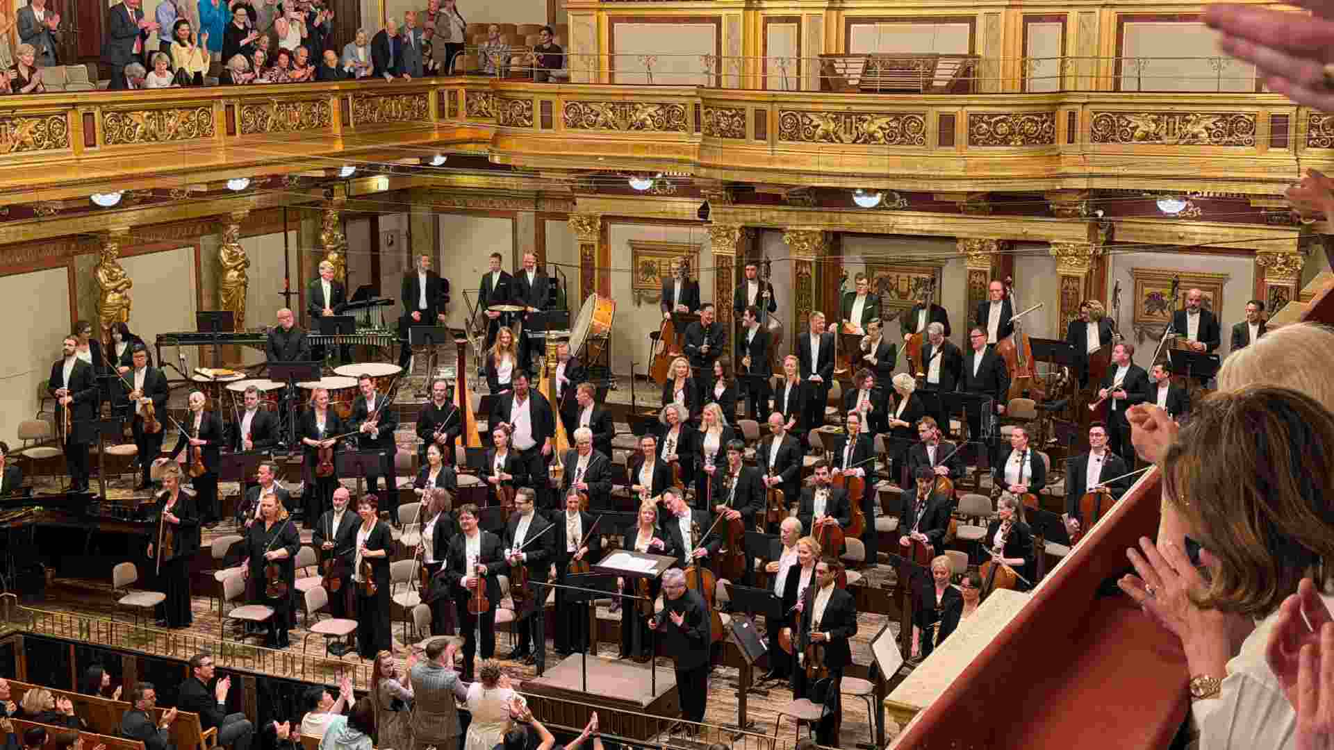 Classical musicians and conductor take a bow before an applauding audience in Vienna.