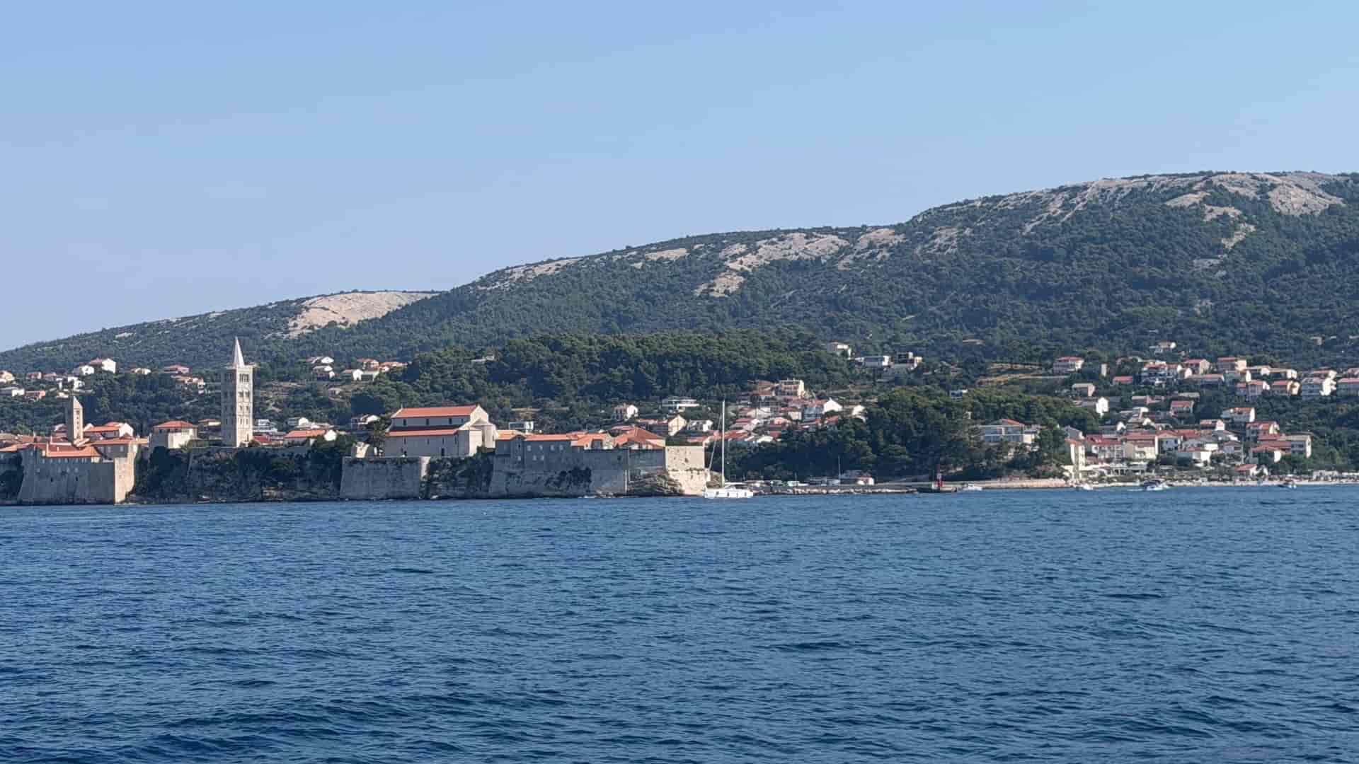 Seaward view of Rab Old Town's fortified walls and Romanesque bell towers along the coast.