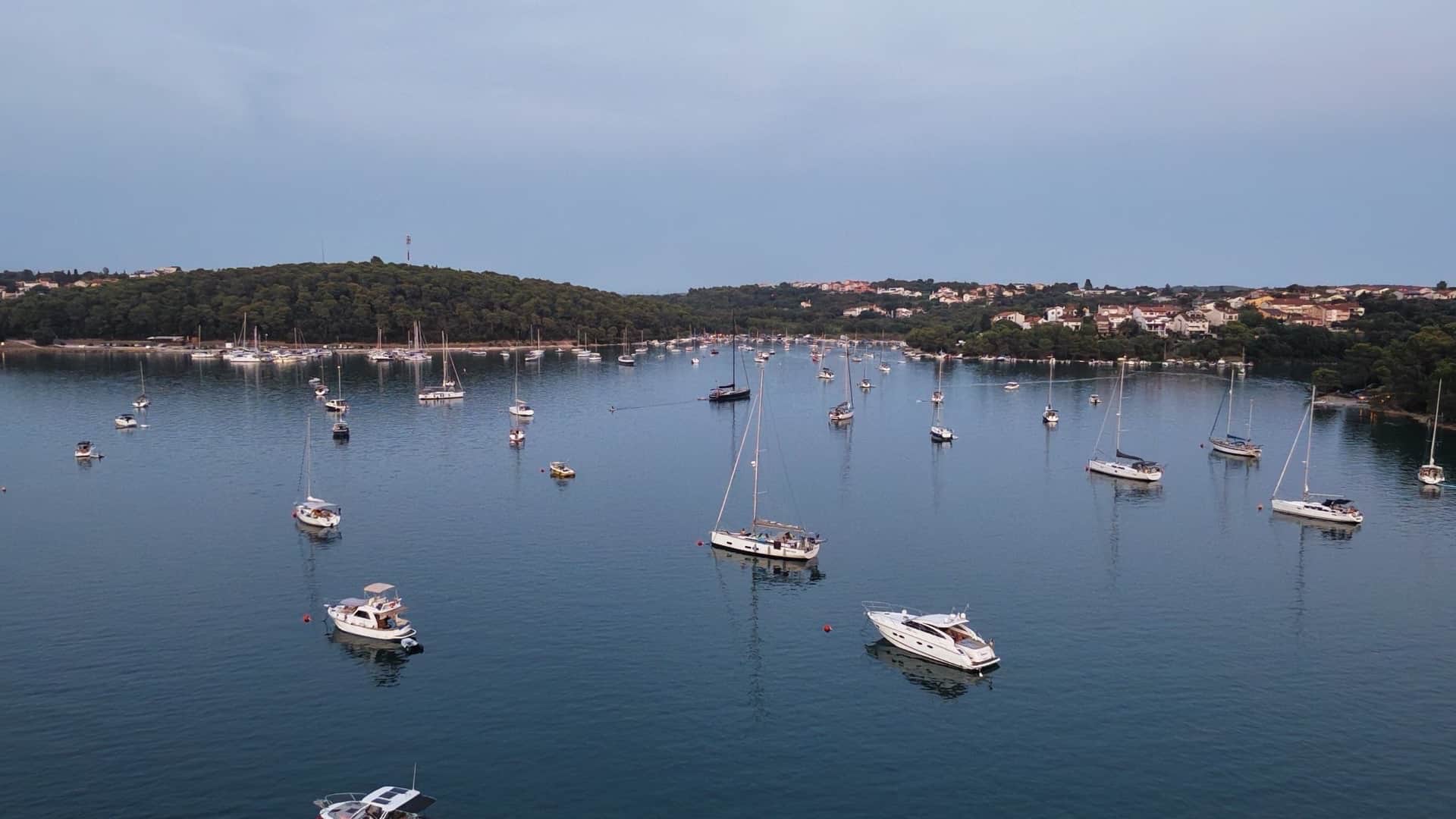 High-angle view of moored yachts resting in the calm waters of Uvala Soline at dusk.