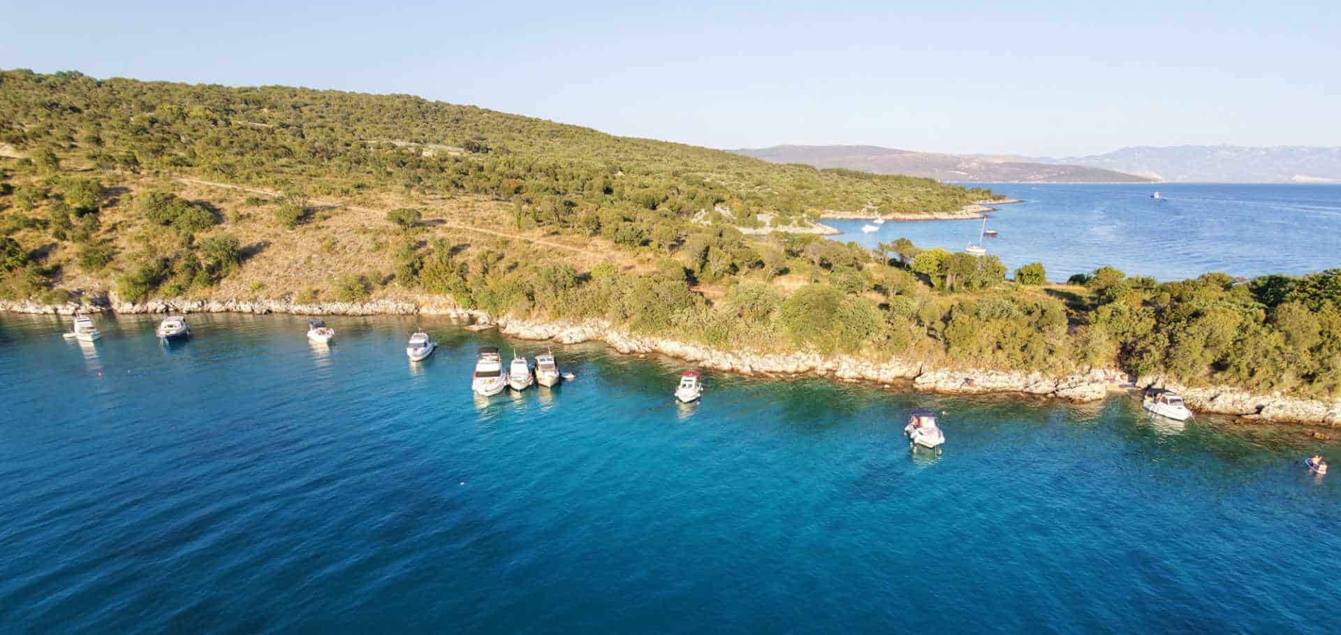 Aerial view of crystal-clear turquoise waters and anchored boats along the Croatian coastline
