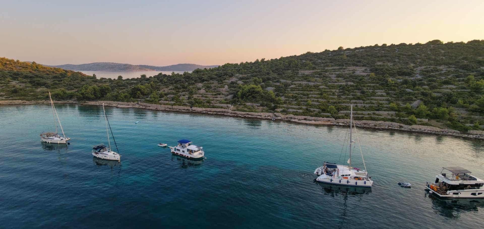 Sailboats anchored in a pristine turquoise cove surrounded by green hills in Croatia