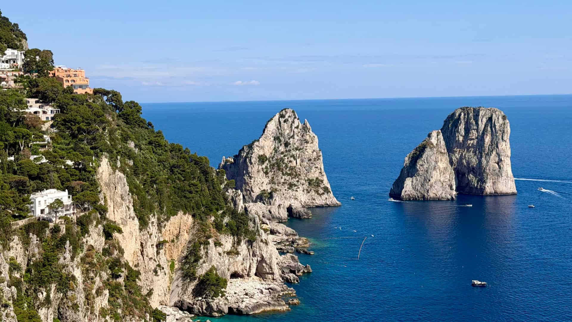 Rugged limestone cliffs rising above the deep blue Tyrrhenian Sea near the Faraglioni rock formations in Capri.