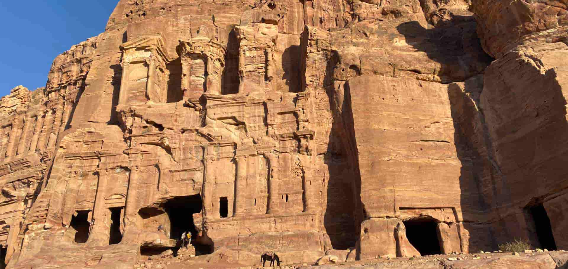 Ornate classical architectural details and carved alcoves cut directly into the sheer red sandstone wall.