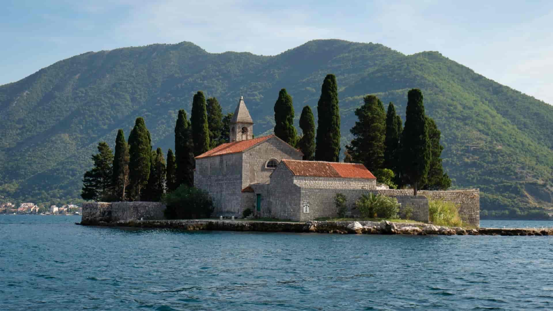 Our Lady of the Rocks island church surrounded by cypress trees in the Bay of Kotor.