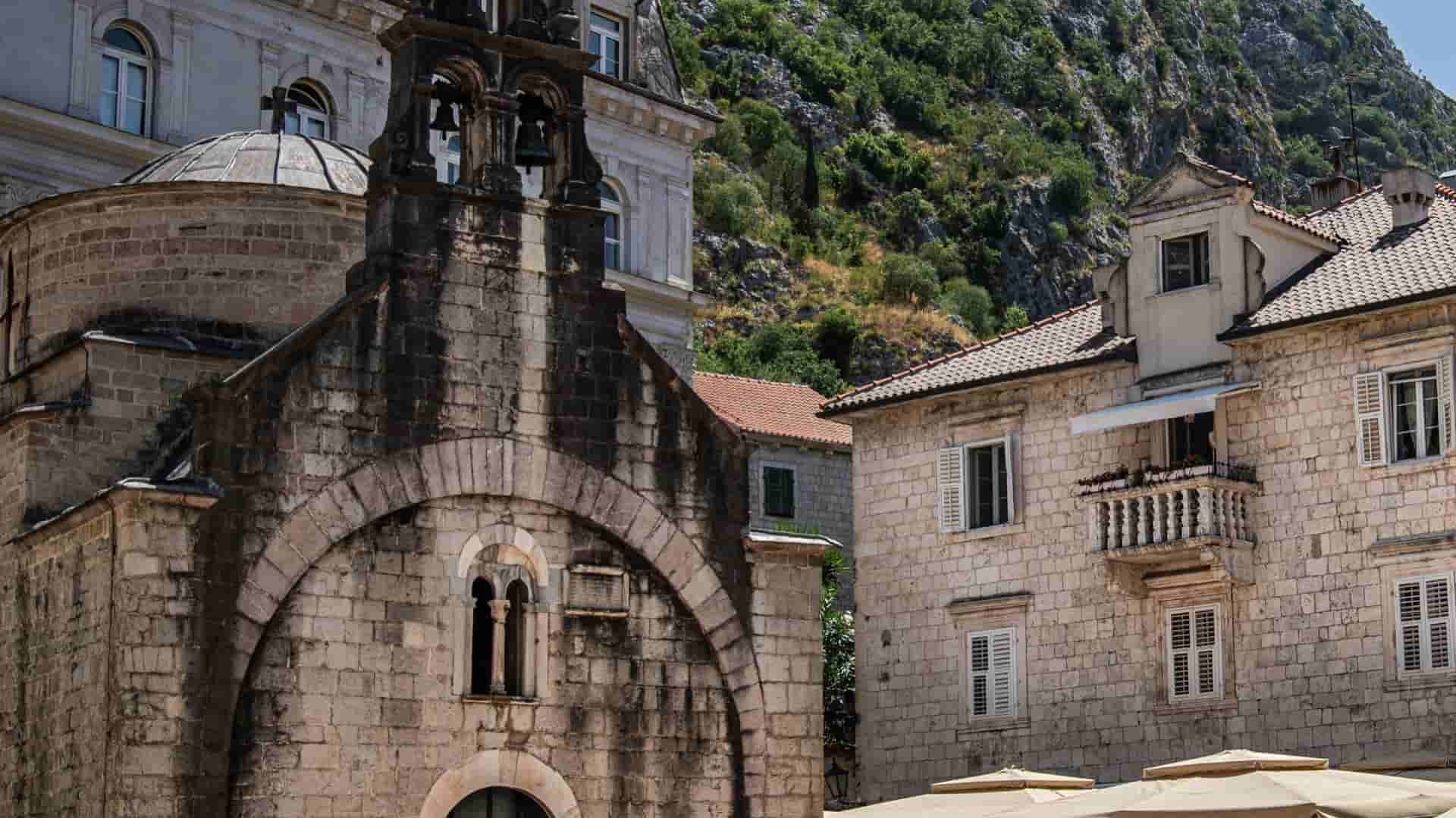 Historic stone church with arched bell tower in Kotor old town plaza.