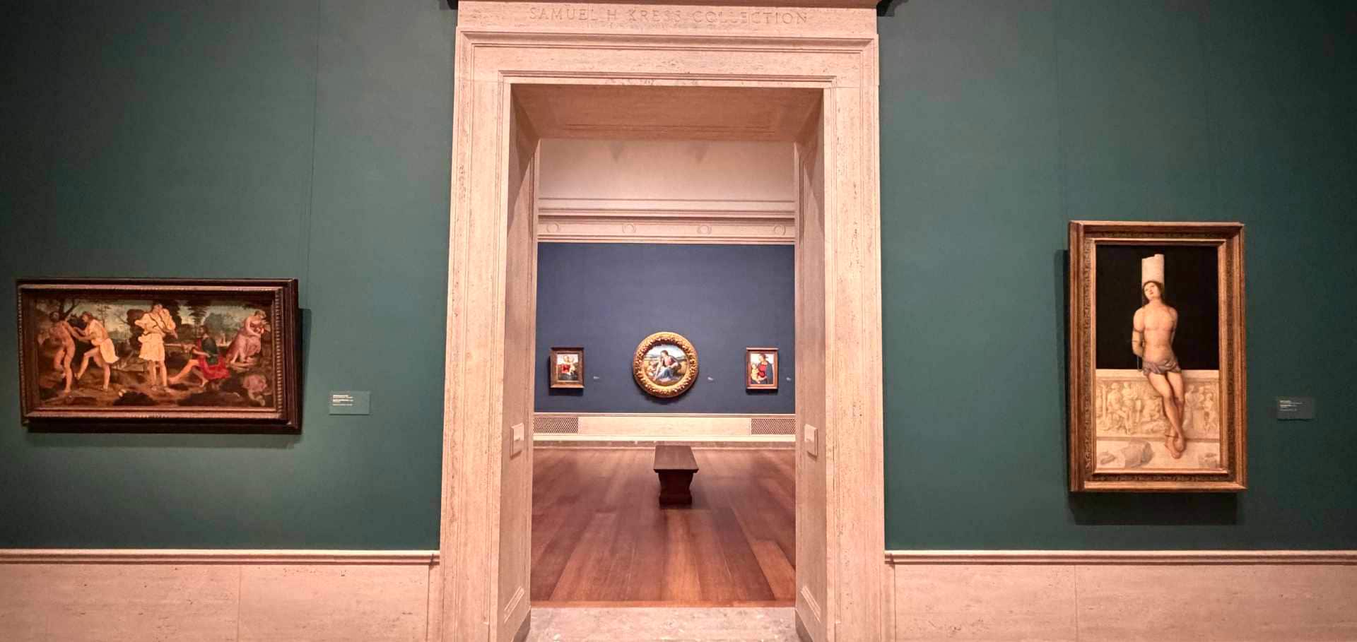Visitors walk through a stone archway into adjoining galleries displaying classical paintings.