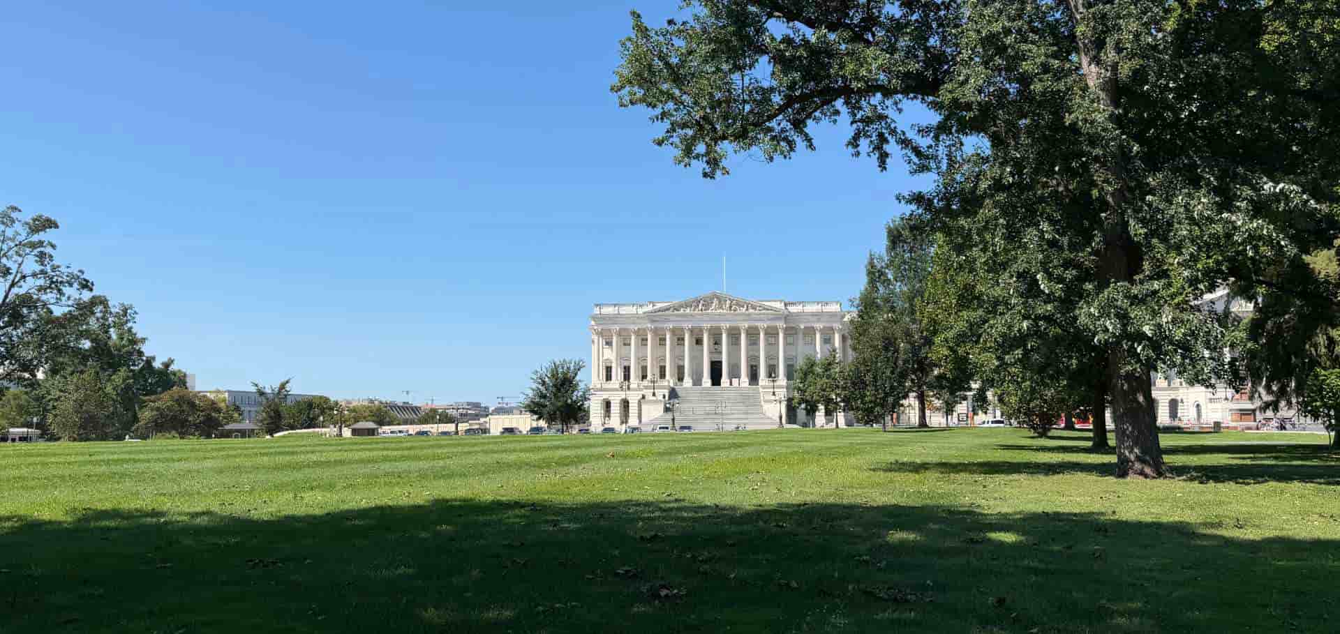 Open green lawn leading toward a neoclassical federal building in Washington D.C.