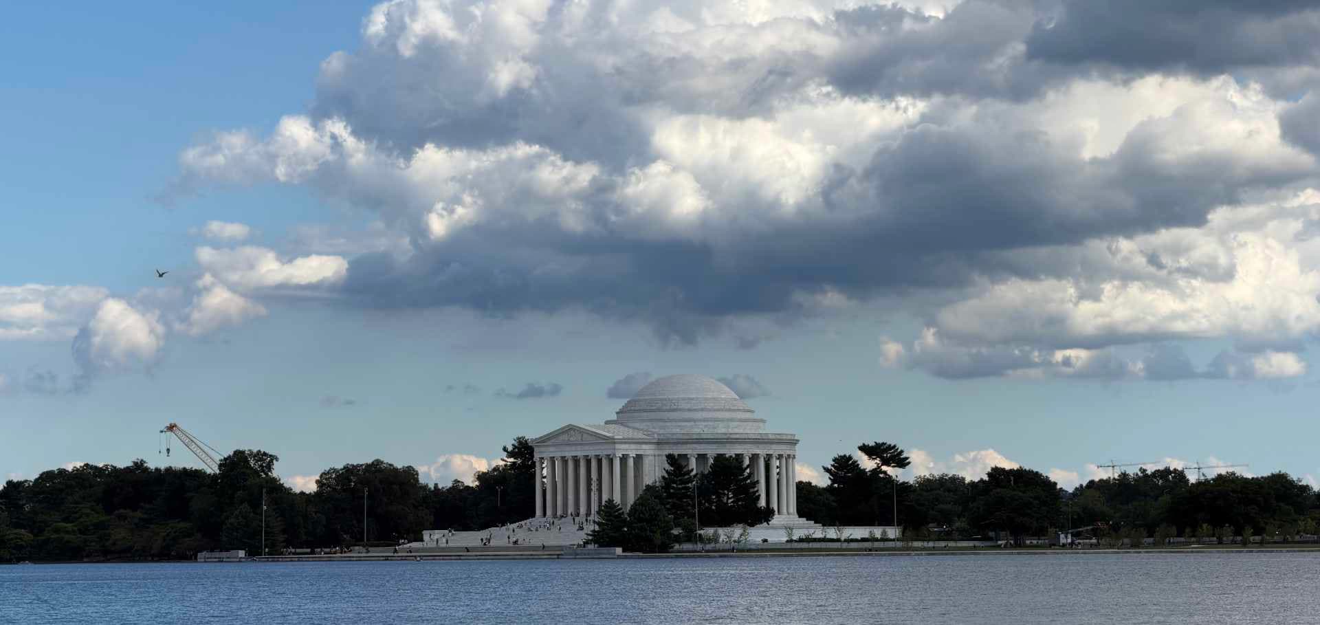 The majestic white marble dome of the Jefferson Memorial framed against dramatic afternoon clouds.