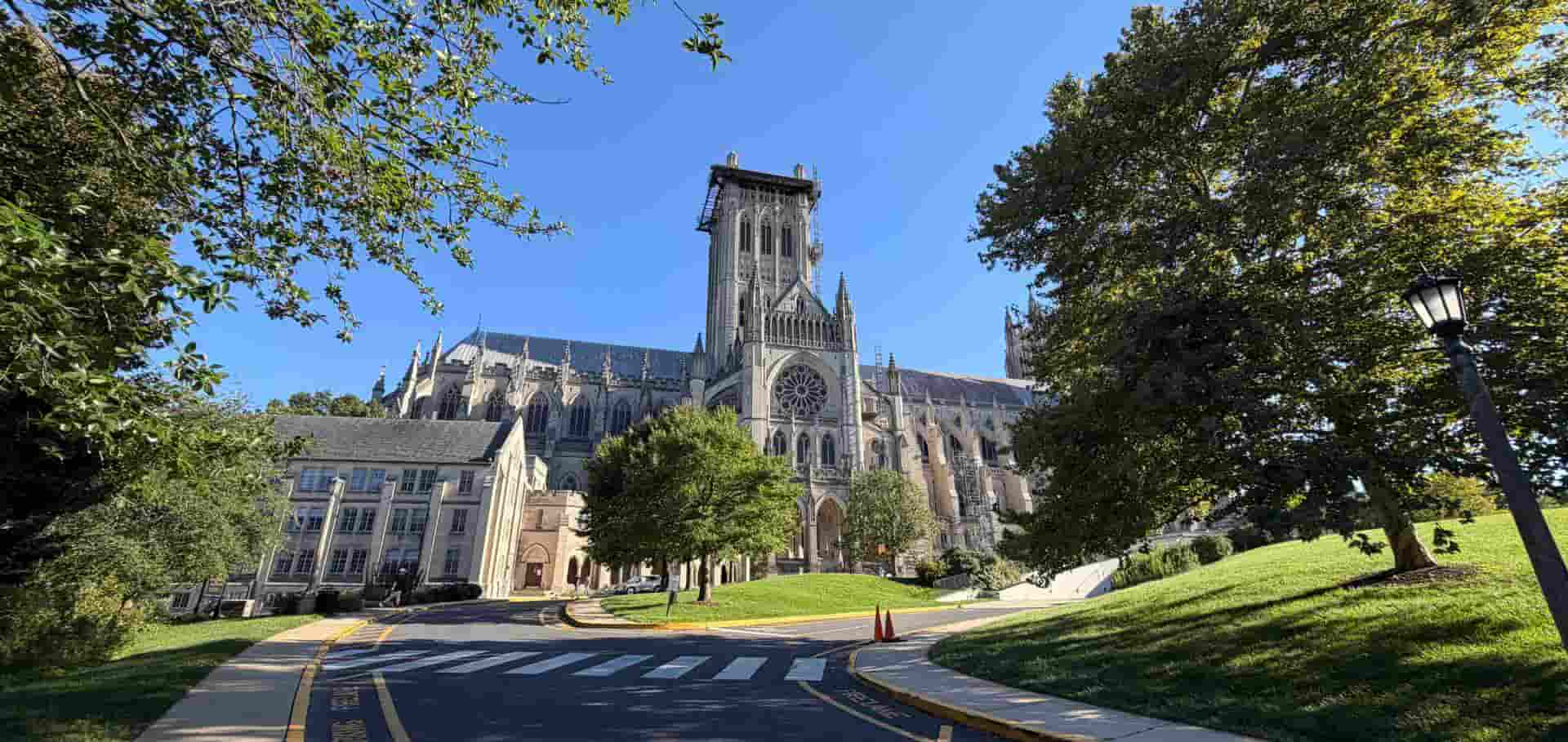 The grand Gothic architecture of the Washington National Cathedral surrounded by lush green trees.