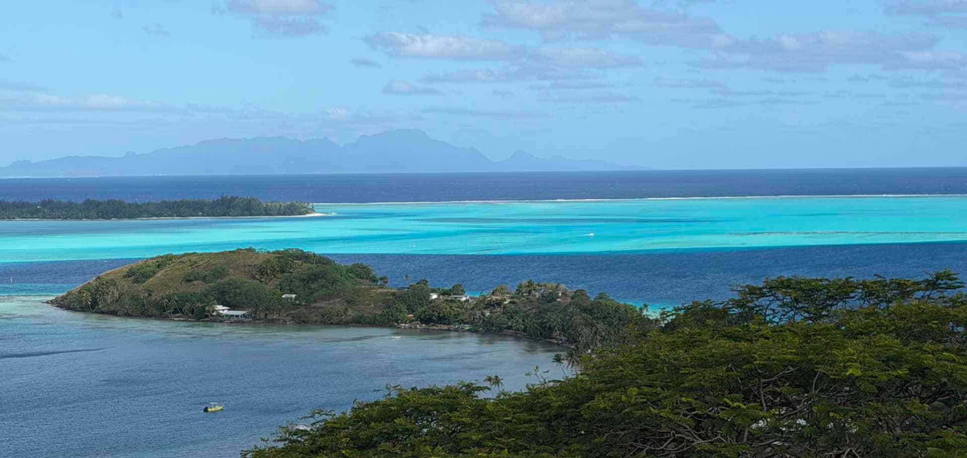 A distant volcanic island silhouette rising above a vast horizon of deep blue ocean water.