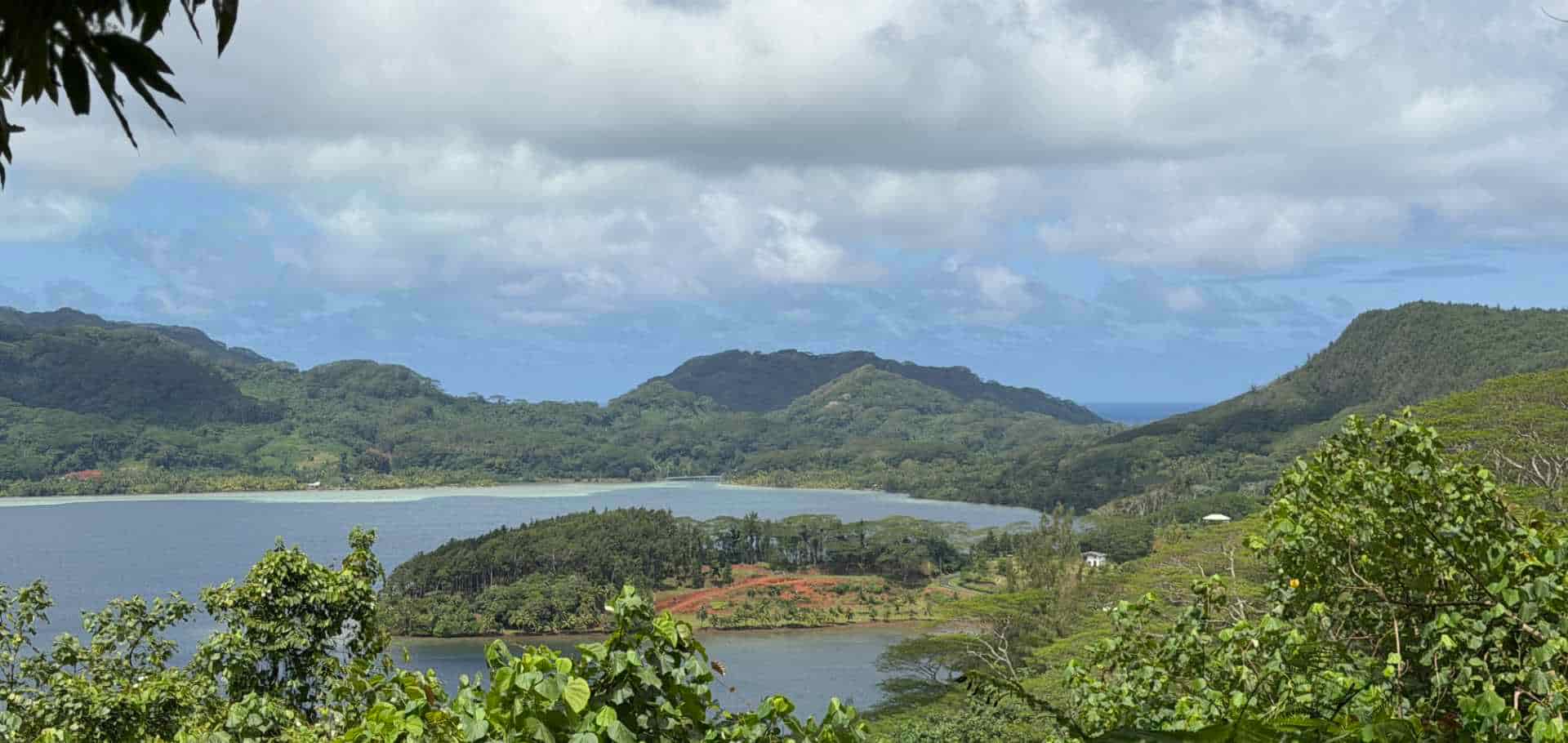 A lush tropical landscape of green mountains surrounding a tranquil blue lagoon in French Polynesia.