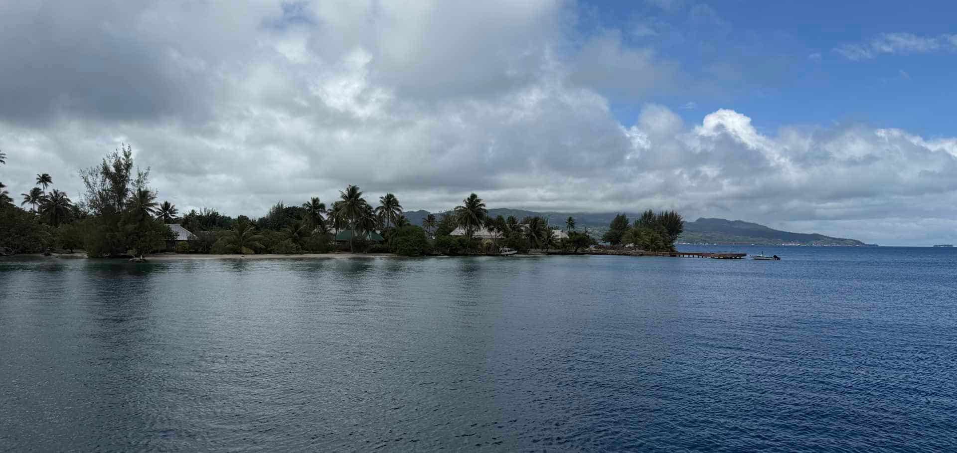 A wooden pier stretching out toward tropical island shores and calm coastal waters.