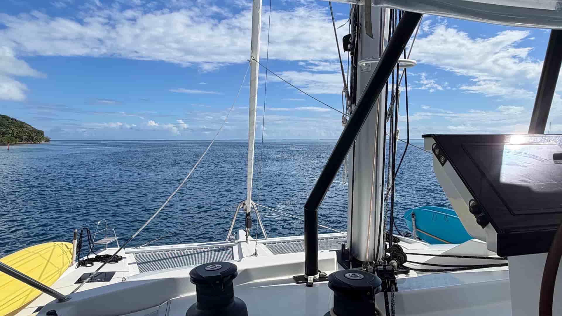 View from the helm of a catamaran looking out over blue ocean waters