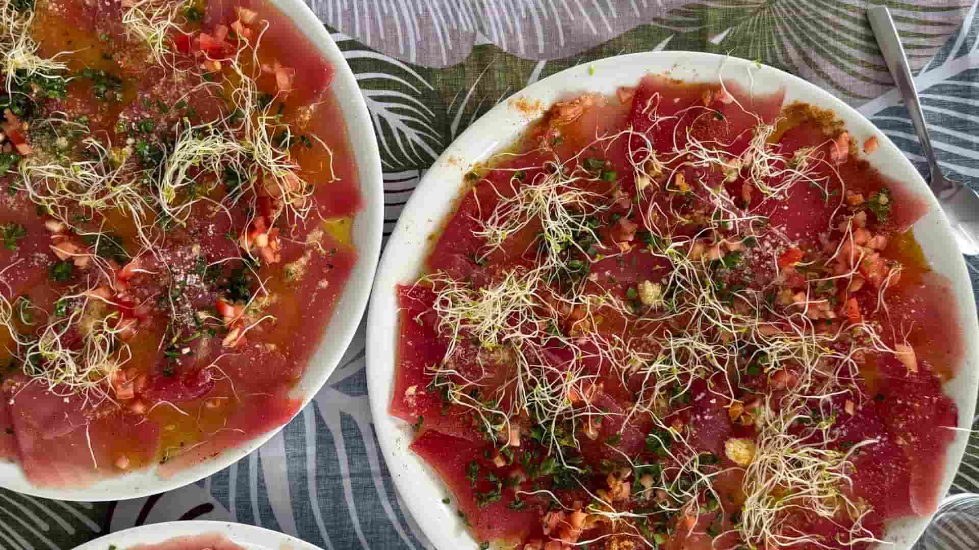 Freshly prepared tuna carpaccio garnished with sprouts on white plates