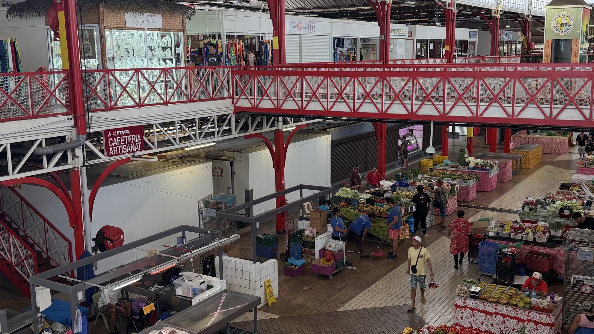 Elevated view of the red steel upper mezzanine and bustling ground floor stalls of Papeete market.