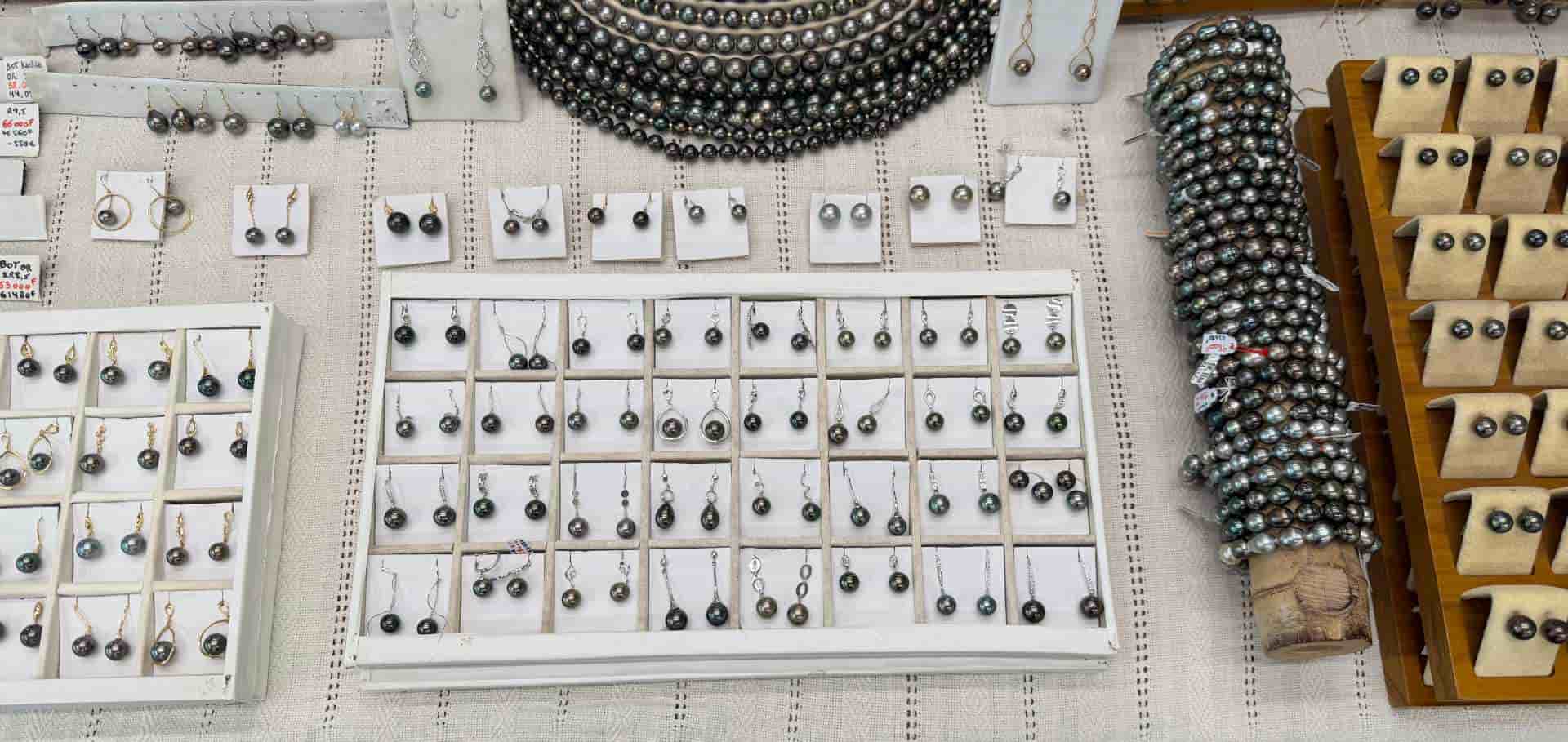 Trays of harvested black pearls sorted by size and luster on a workbench.