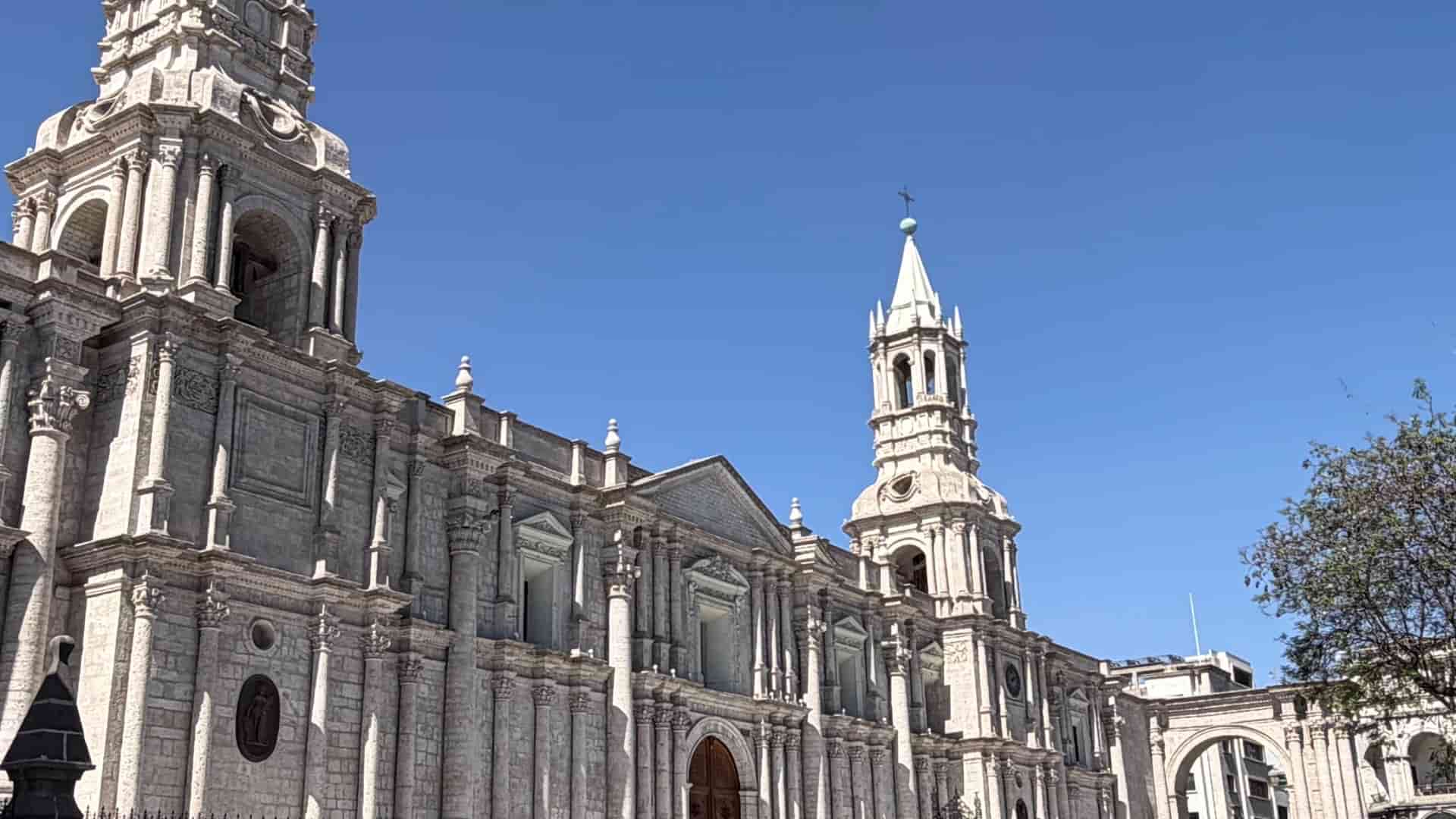 Ornate facade and twin bell towers of the grand Cathedral of Arequipa under a clear blue sky.