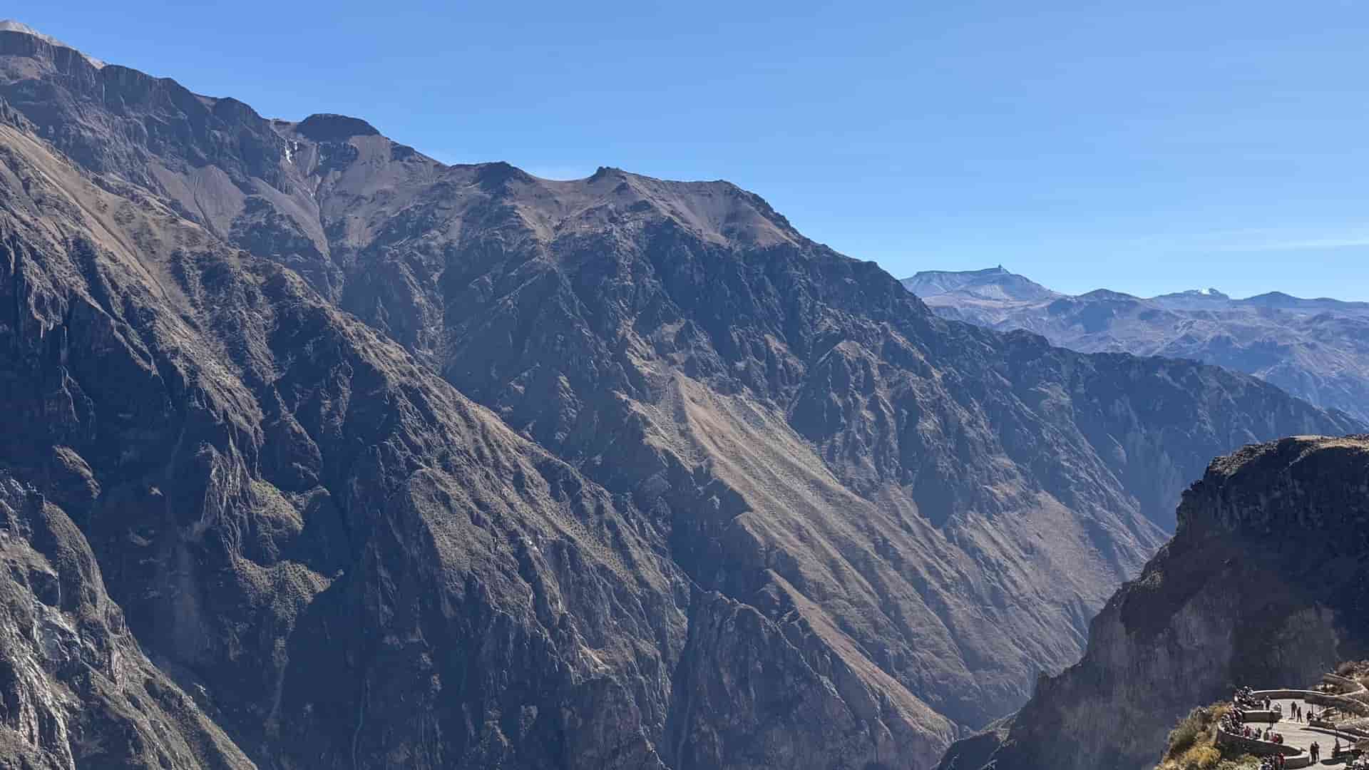 Rugged brown rock cliffs and deep mountain ridges plunging into Colca Canyon.