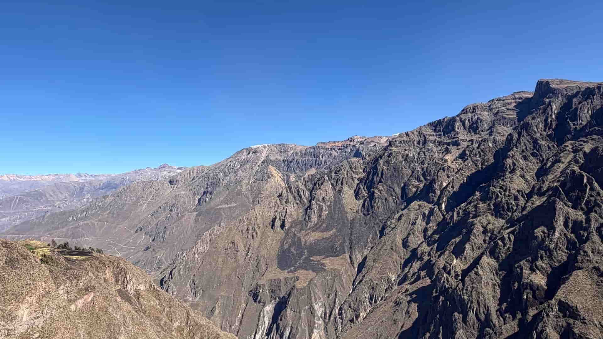 Expansive view of jagged mountain peaks stretching across the Colca Valley.