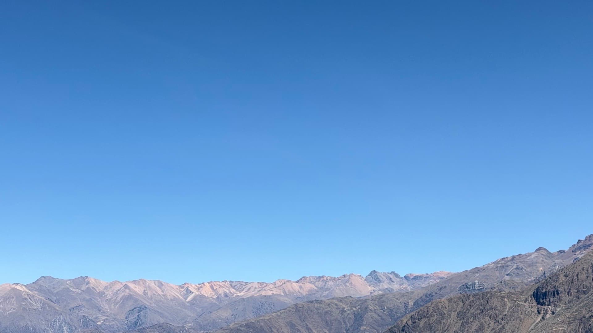 Panoramic view of distant mountain ranges under a bright blue sky.