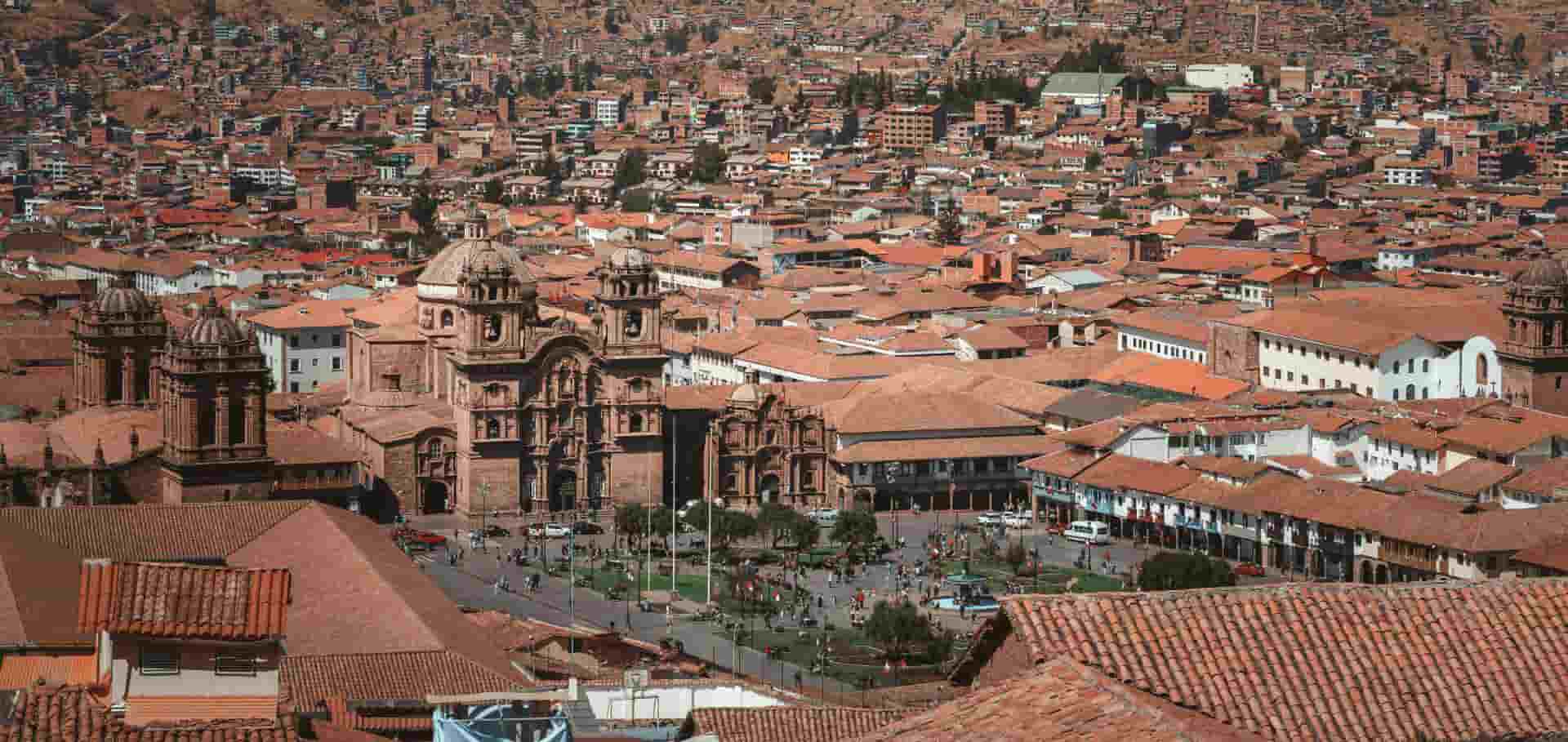 Panoramic aerial view of red tile rooftops and historic colonial churches across Cusco.