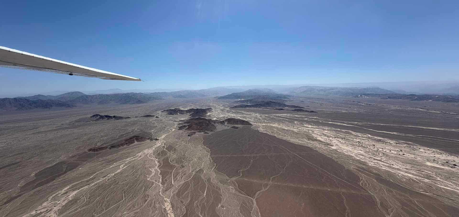 Expansive landscape of the arid Nazca plateau under a clear blue sky.