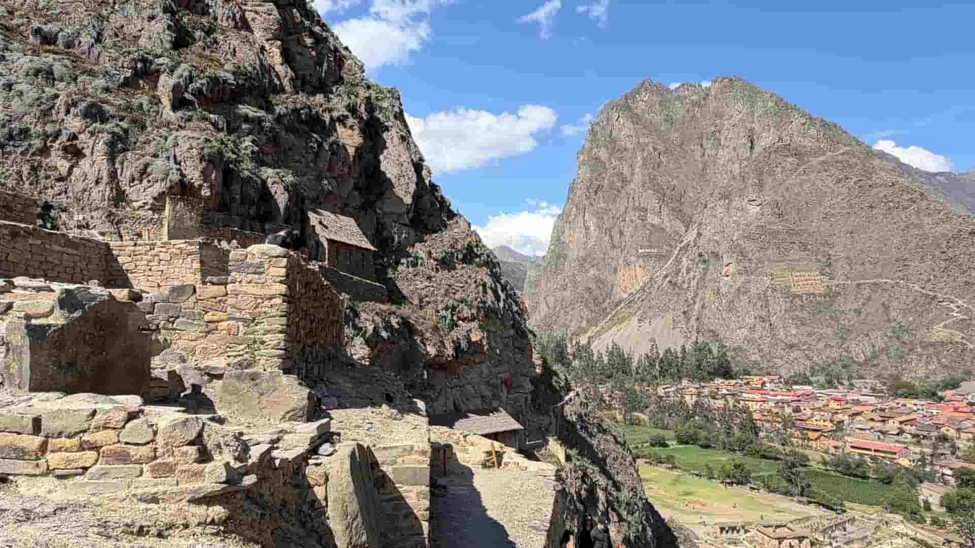 Ancient stone ruins perched on a rocky cliff overlooking the town of Ollantaytambo.