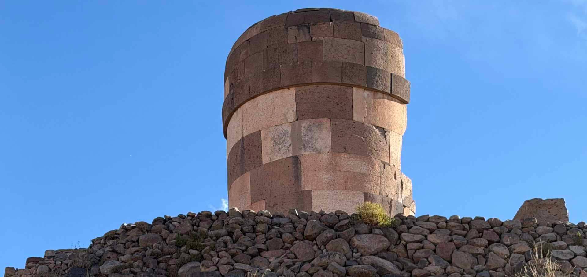 Detailed view of a cylindrical stone tower built from alternating colored blocks against the sky.