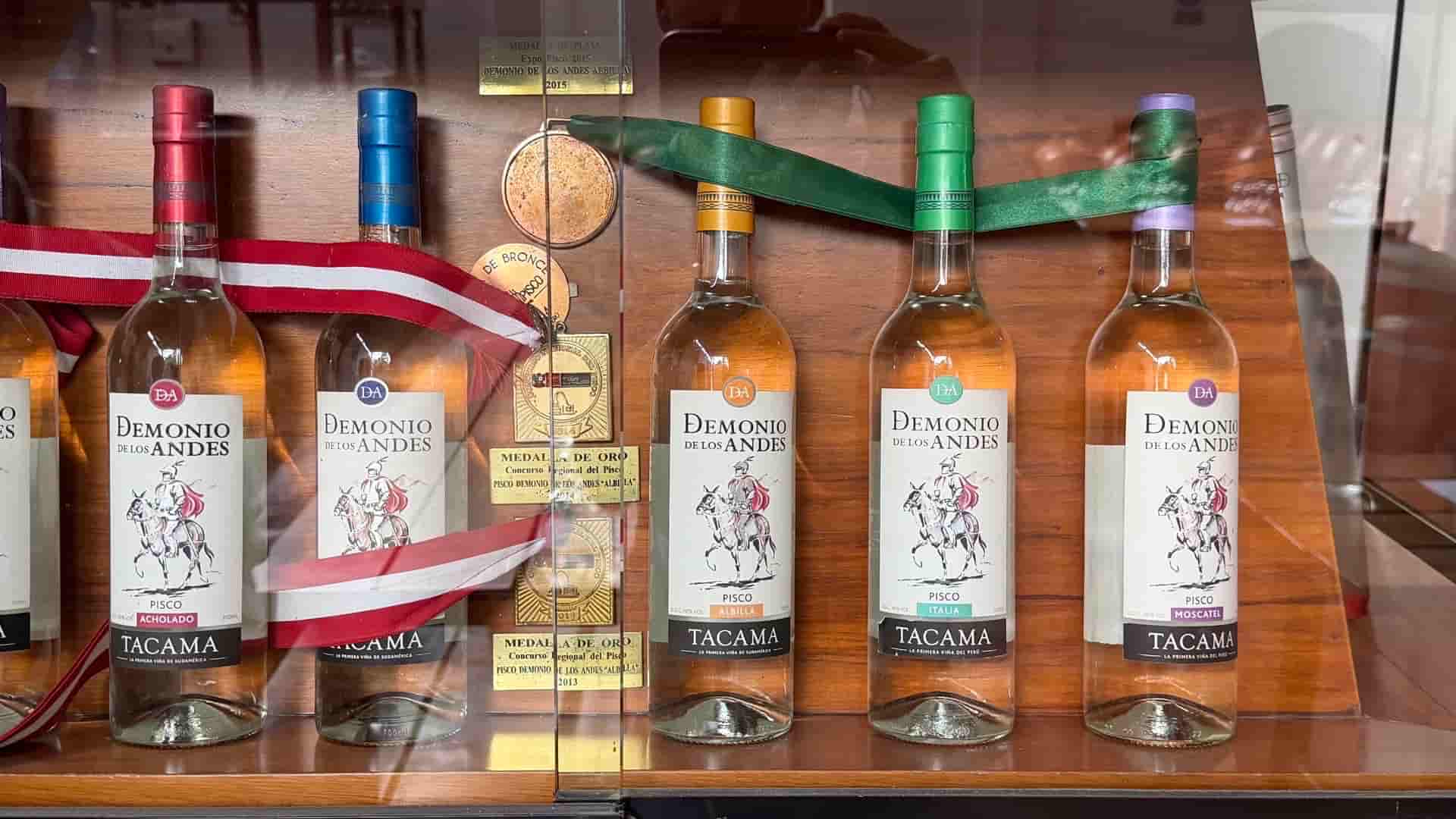Display case containing various bottles of Demonio de los Andes pisco with medals at Tacama winery.