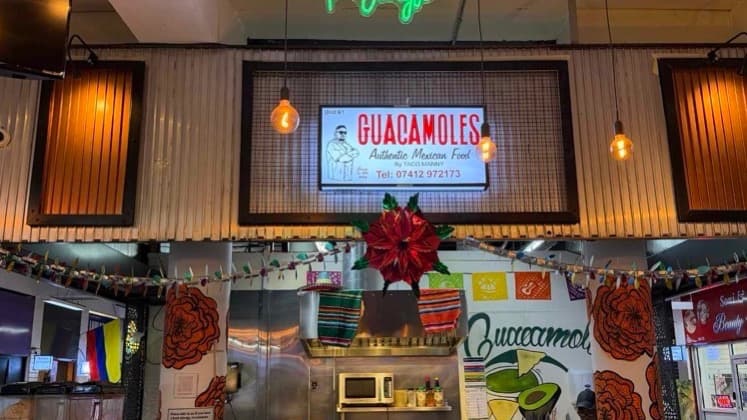 Overhead view of the bustling Guacamoles counter featuring colorful hanging banners.